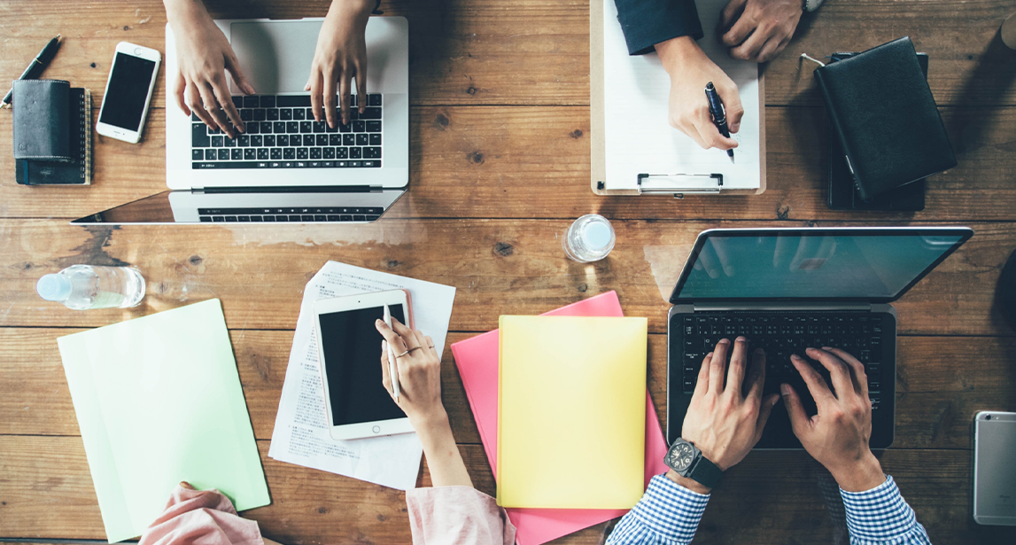 机でパソコンや書き物をしている4人の写真